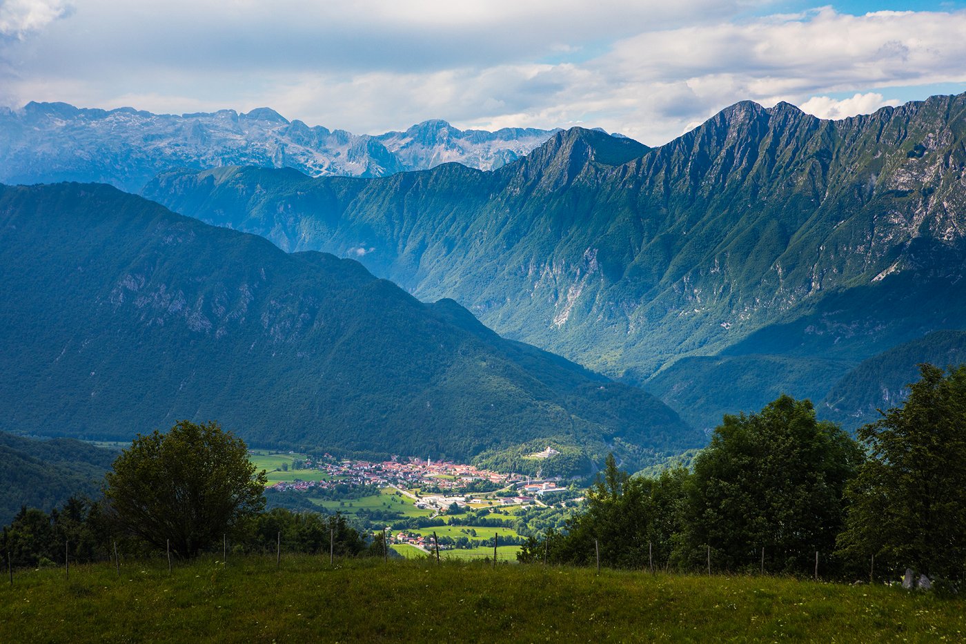 Razgled na mesto Kobarid, razsvetljeno s soncem, v ozadju lokalni hribi