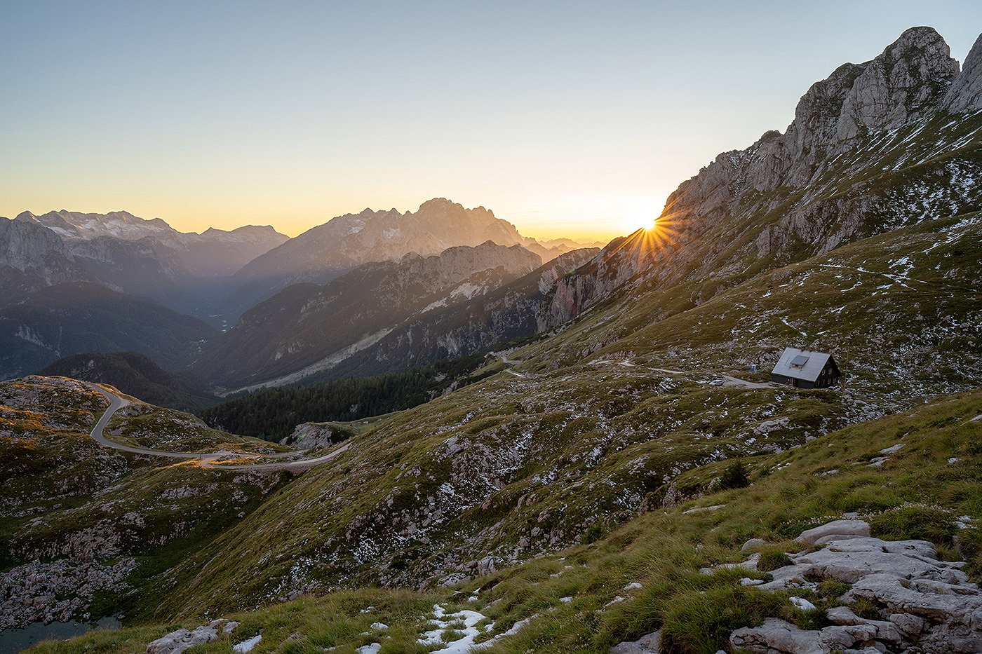 il sole tramonta dietro le montagne che circondano il rifugio Mangart