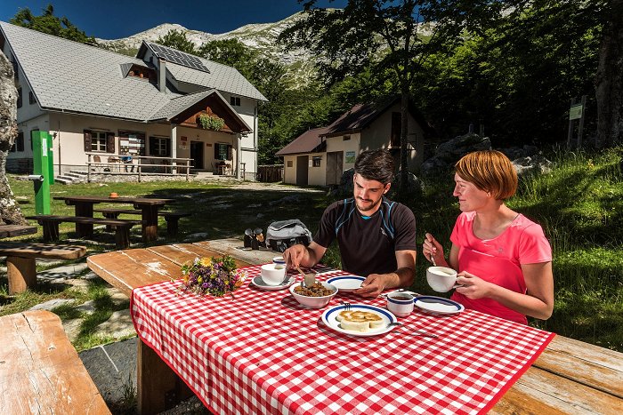 Planinca uživata v dobri domači hrani pred kočo