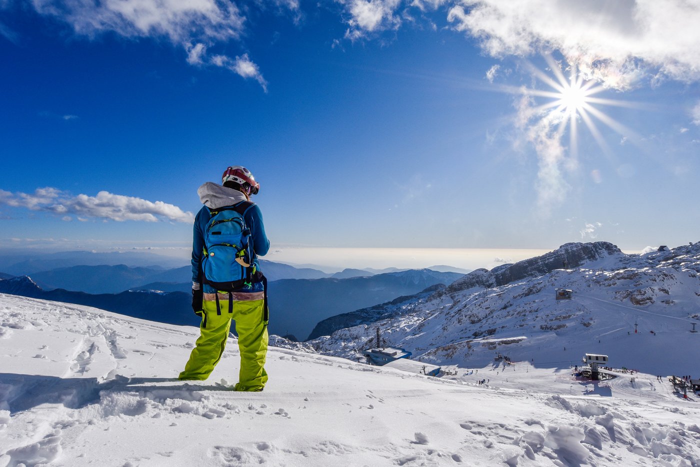 Von der sonnendurchfluteten Skipiste genießt der Skifahrer den Blick ins Tal.